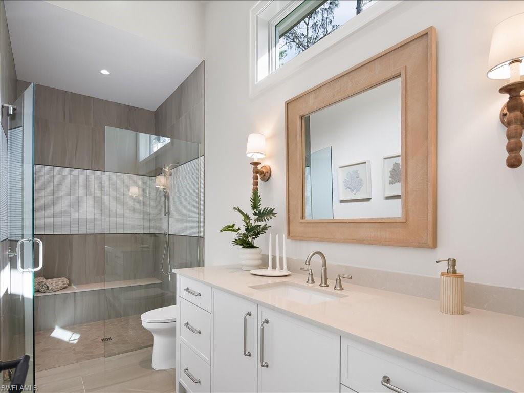 6730 Sable Ridge Lane Naples, FL 34109 - Photo 29 of 50 a bathroom with a granite countertop sink a toilet and a mirror