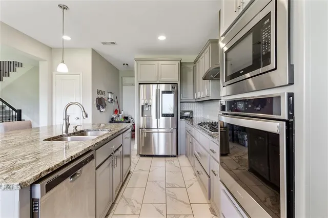 a kitchen with stainless steel appliances granite countertop a stove top oven a refrigerator a sink and chairs