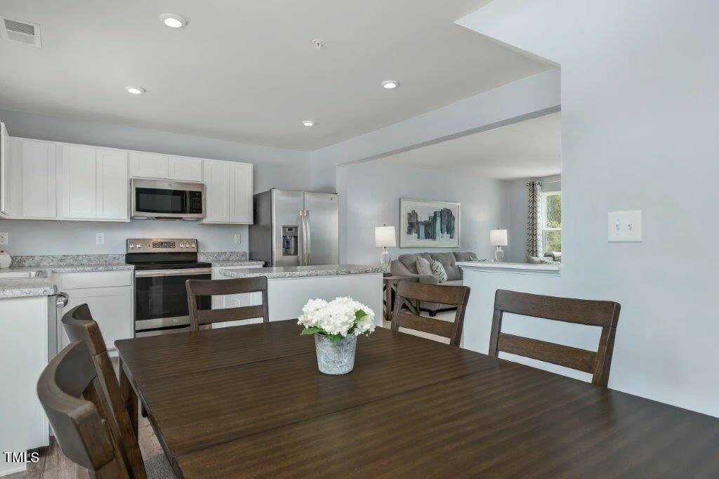 125 Sunny Acrs Road Raleigh, NC 27603 - Photo 5 of 19 a kitchen with sink wooden floor and stainless steel appliances