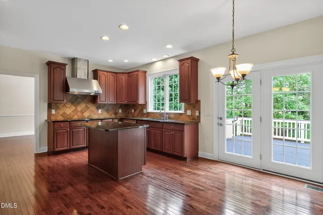 a kitchen with stainless steel appliances granite countertop a refrigerator a stove and a wooden floors
