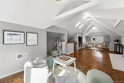 a living room with dining table a rug couches and a dining table with wooden floor