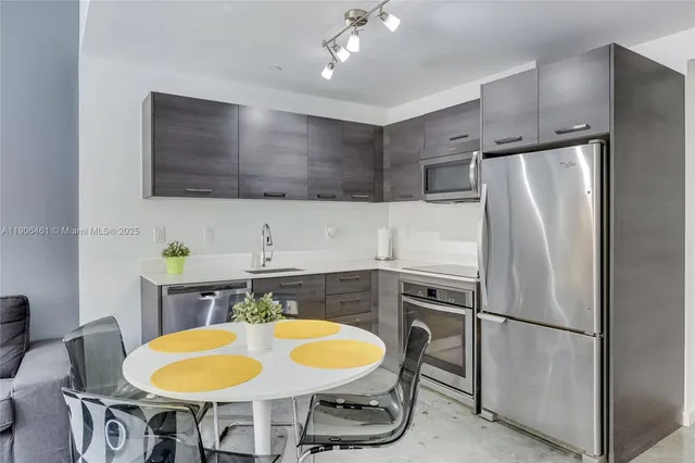 a kitchen with stainless steel appliances granite countertop a sink refrigerator and cabinets