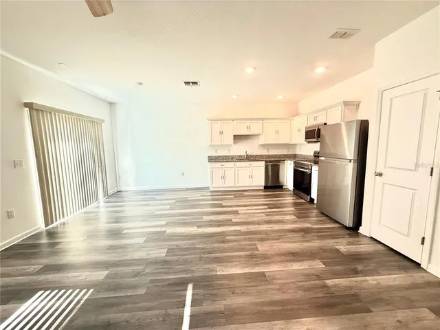 a kitchen with granite countertop a refrigerator and a stove top oven