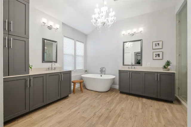 a bathroom with a double vanity sink a large mirror and a bathtub