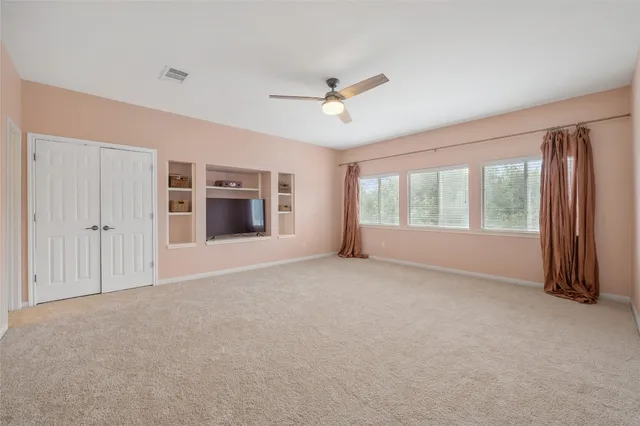 a view of empty room with windows and ceiling fan