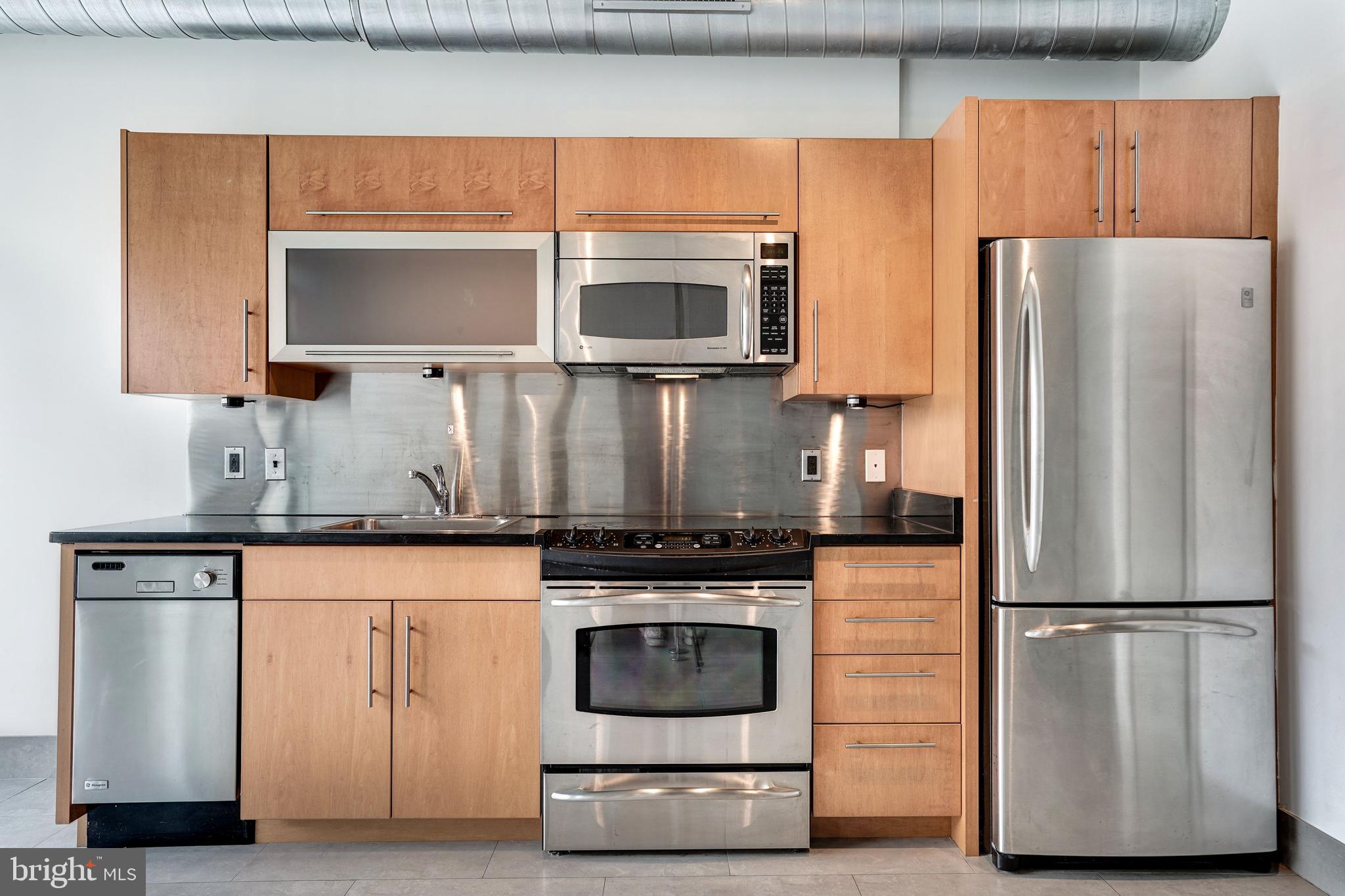 1133 14th Street Northwest, Unit 809 Washington, DC 20005 - Photo 12 of 27 a kitchen with granite countertop a refrigerator stove and microwave