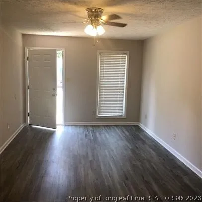 an empty room with wooden floor cabinet and windows