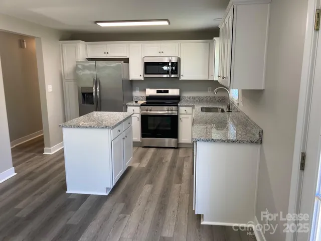 a kitchen with granite countertop a stove top oven and cabinets