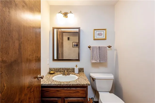 a bathroom with a granite countertop toilet a sink and mirror