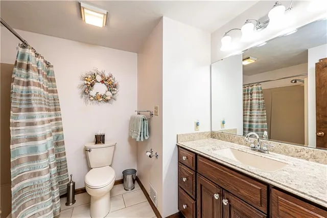 a bathroom with a granite countertop toilet sink and mirror