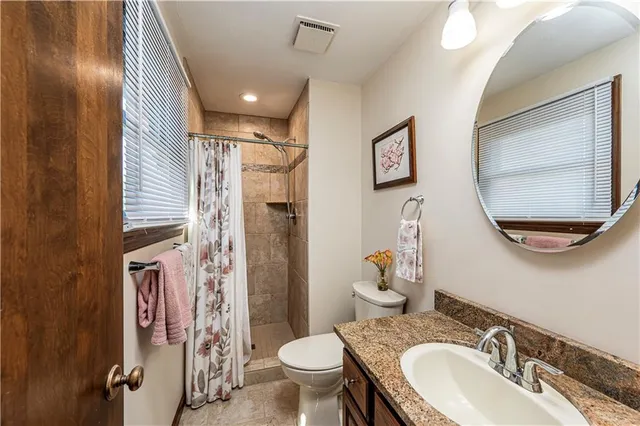 a bathroom with a granite countertop toilet a sink and a mirror