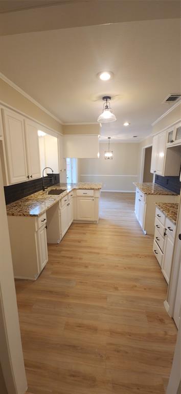 2821 Windy Drive Commerce, TX 75428 - Photo 14 of 25 a large white kitchen with kitchen island a stove a sink dishwasher and white cabinets with wooden floor
