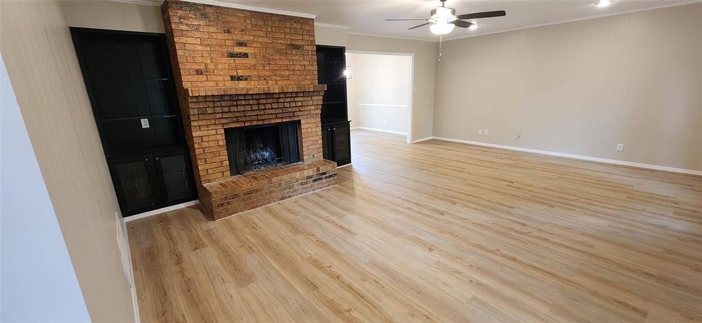 2821 Windy Drive Commerce, TX 75428 - Photo 21 of 25 an empty room with wooden floor a fireplace and entryway