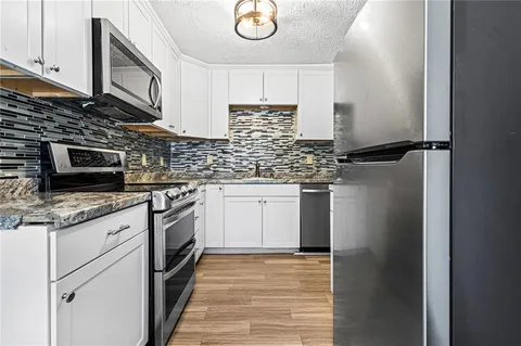 a kitchen with stainless steel appliances granite countertop a refrigerator a stove top oven a sink and dishwasher