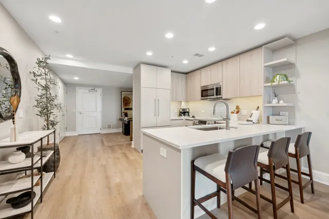 a kitchen with stainless steel appliances kitchen island granite countertop a stove a sink a dining table and chairs with wooden floor