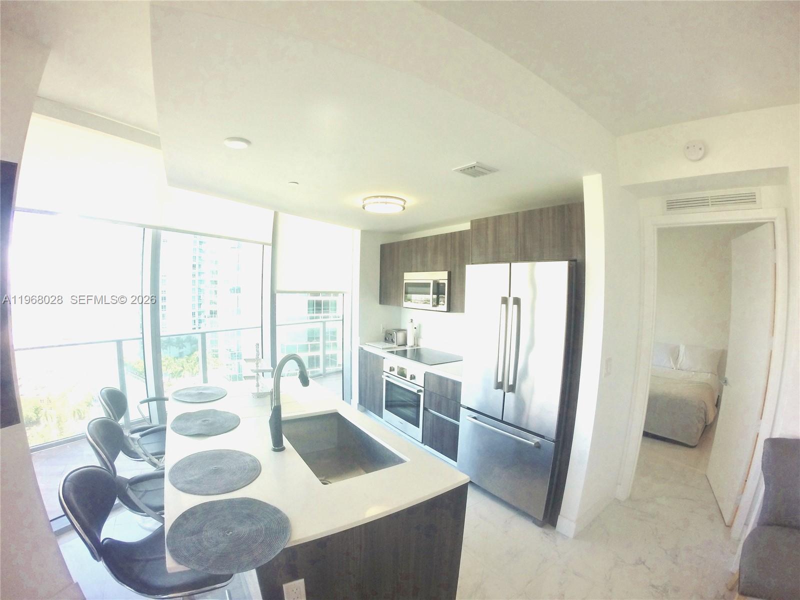 488 Northeast 18th Street, Unit 2001 Miami, FL 33132 - Photo 3 of 26 a kitchen with stainless steel appliances granite countertop a refrigerator a sink a stove and white cabinets