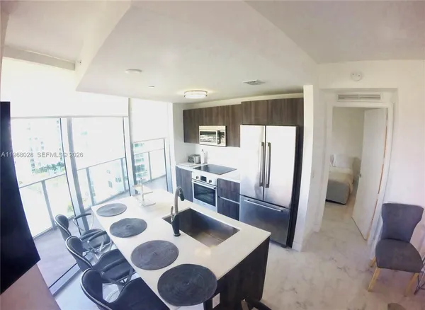 a view of a dining room with furniture a kitchen and wooden floor