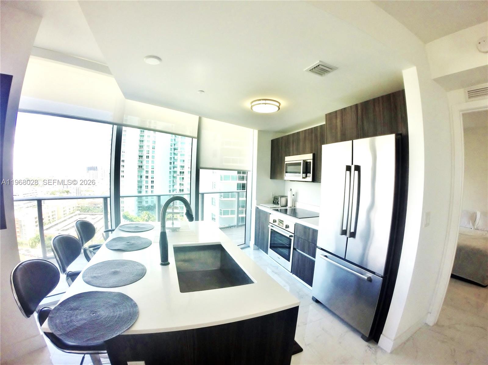 488 Northeast 18th Street, Unit 2001 Miami, FL 33132 - Photo 5 of 26 a kitchen with stainless steel appliances granite countertop a refrigerator a stove and white cabinets with wooden floor