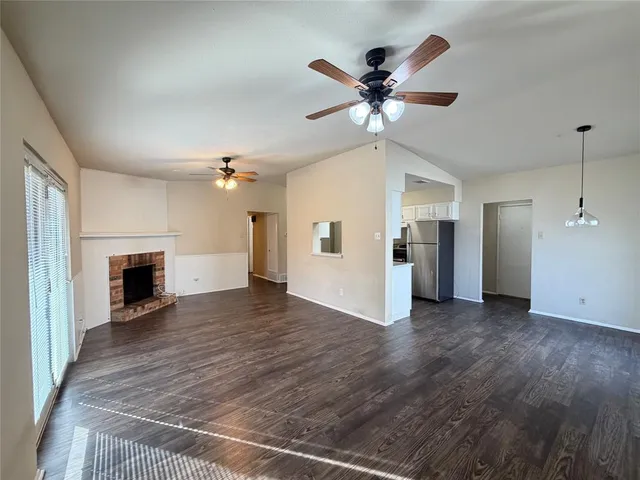 a view of a livingroom with a ceiling fan a fireplace and wooden floor