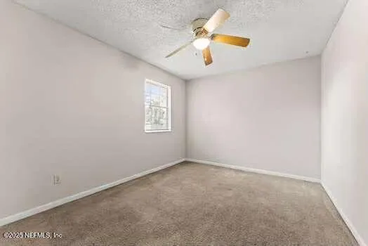 an empty room with windows and chandelier fan