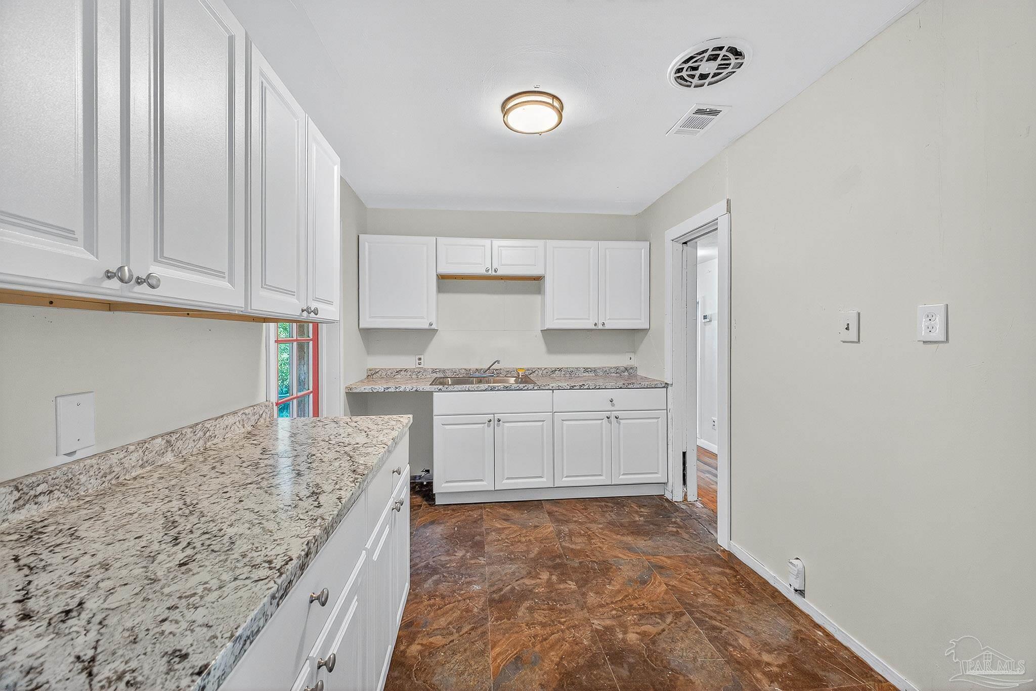 6571 Cedar Street Milton, FL 32570 - Photo 13 of 47 a kitchen with granite countertop a sink stove and cabinets