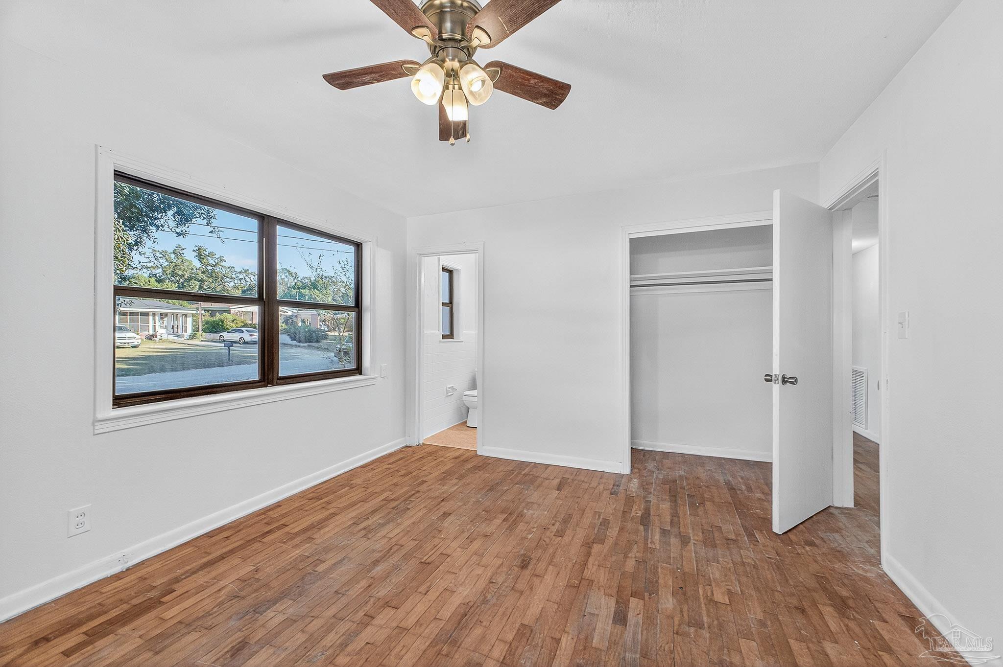 6571 Cedar Street Milton, FL 32570 - Photo 28 of 47 an empty room with wooden floor chandelier fan and windows