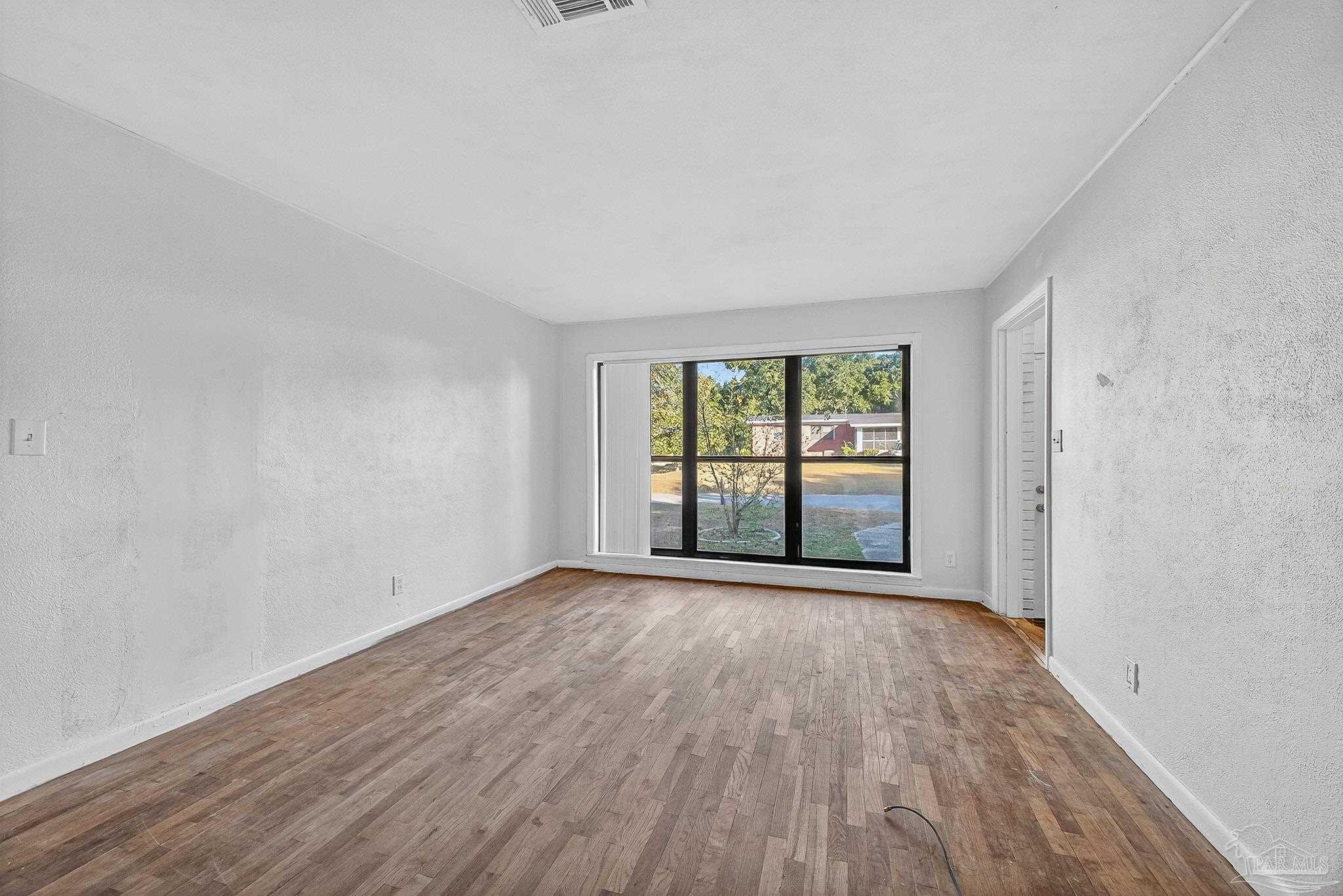 6571 Cedar Street Milton, FL 32570 - Photo 8 of 47 an empty room with wooden floor and windows