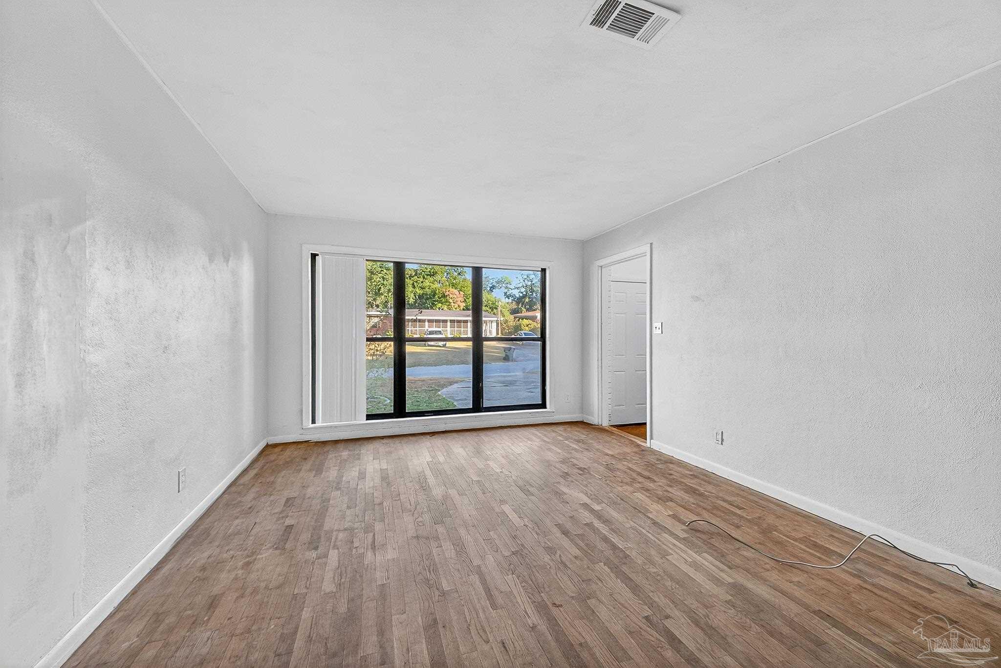 6571 Cedar Street Milton, FL 32570 - Photo 9 of 47 an empty room with wooden floor and windows