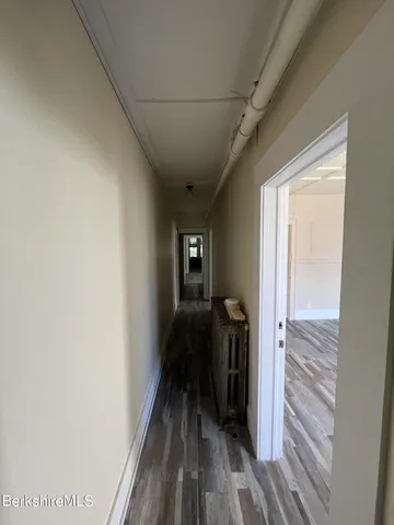 a view of a hallway with wooden floor and a bathroom
