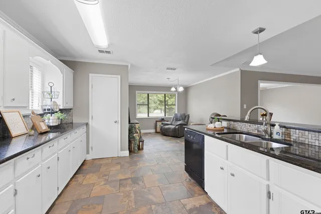 a large white kitchen with a lot of counter space and a sink