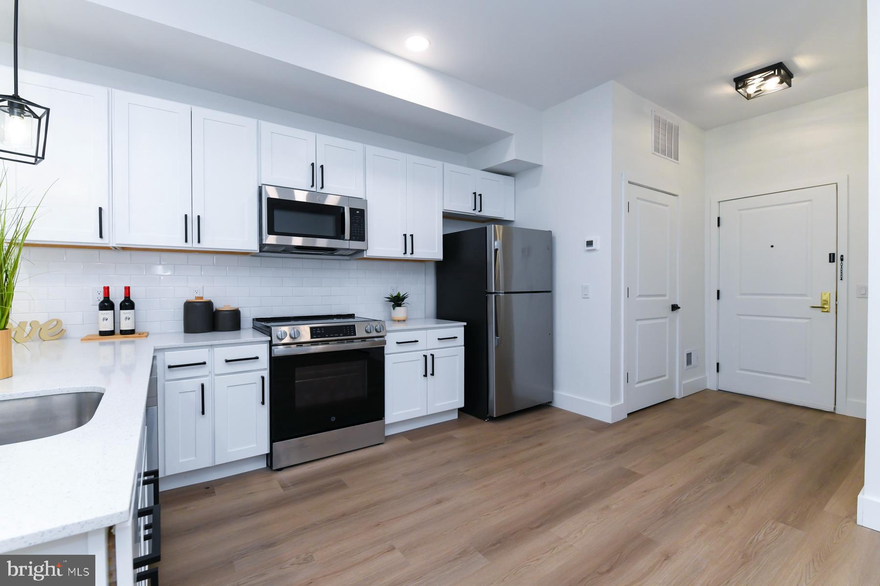 100 Aura Road, Unit 110 Clayton, NJ 08312 - Photo 7 of 21 a kitchen with stainless steel appliances granite countertop a refrigerator stove a sink and dishwasher with wooden floor