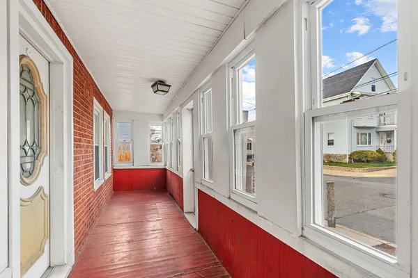 an empty room with wooden floor and windows with curtains