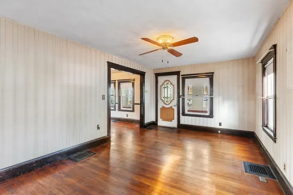 a view of an empty room with window and wooden floor