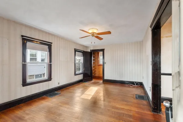 a view of an empty room with window and wooden floor