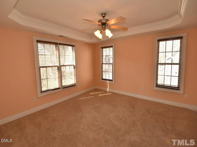 an empty room with windows and chandelier fan