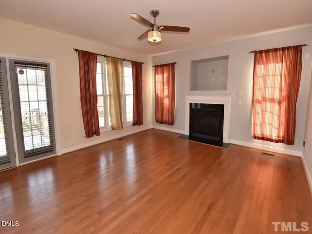 a view of an empty room with window and wooden floor
