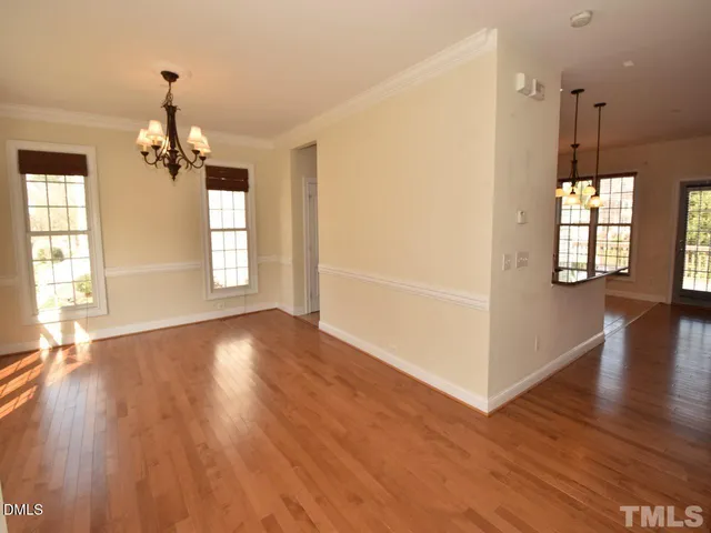 an empty room with wooden floor windows and chandelier