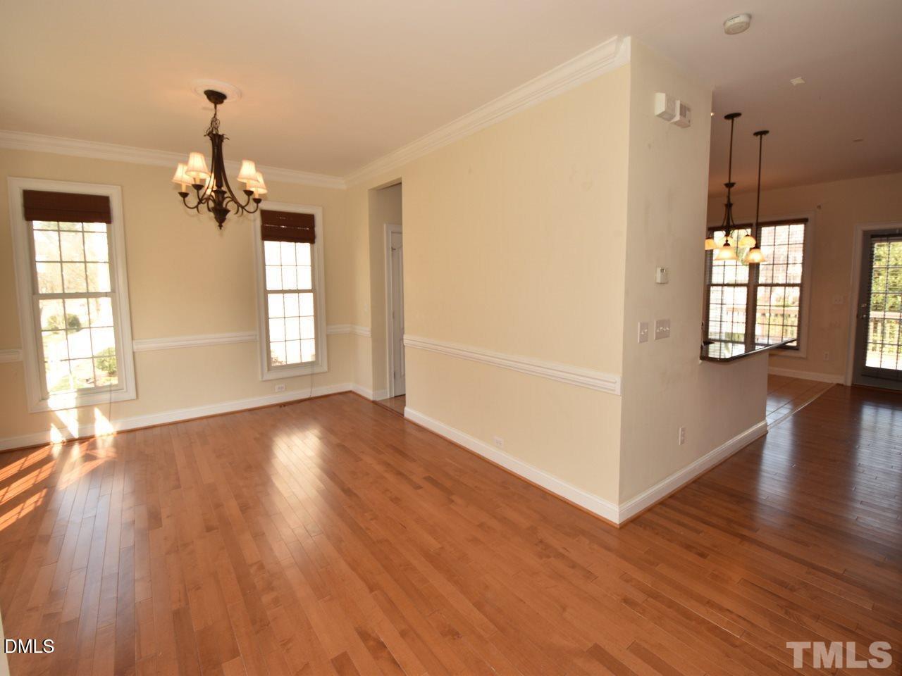 118 Fort Jackson Road Morrisville, NC 27560 - Photo 3 of 21 an empty room with wooden floor windows and chandelier