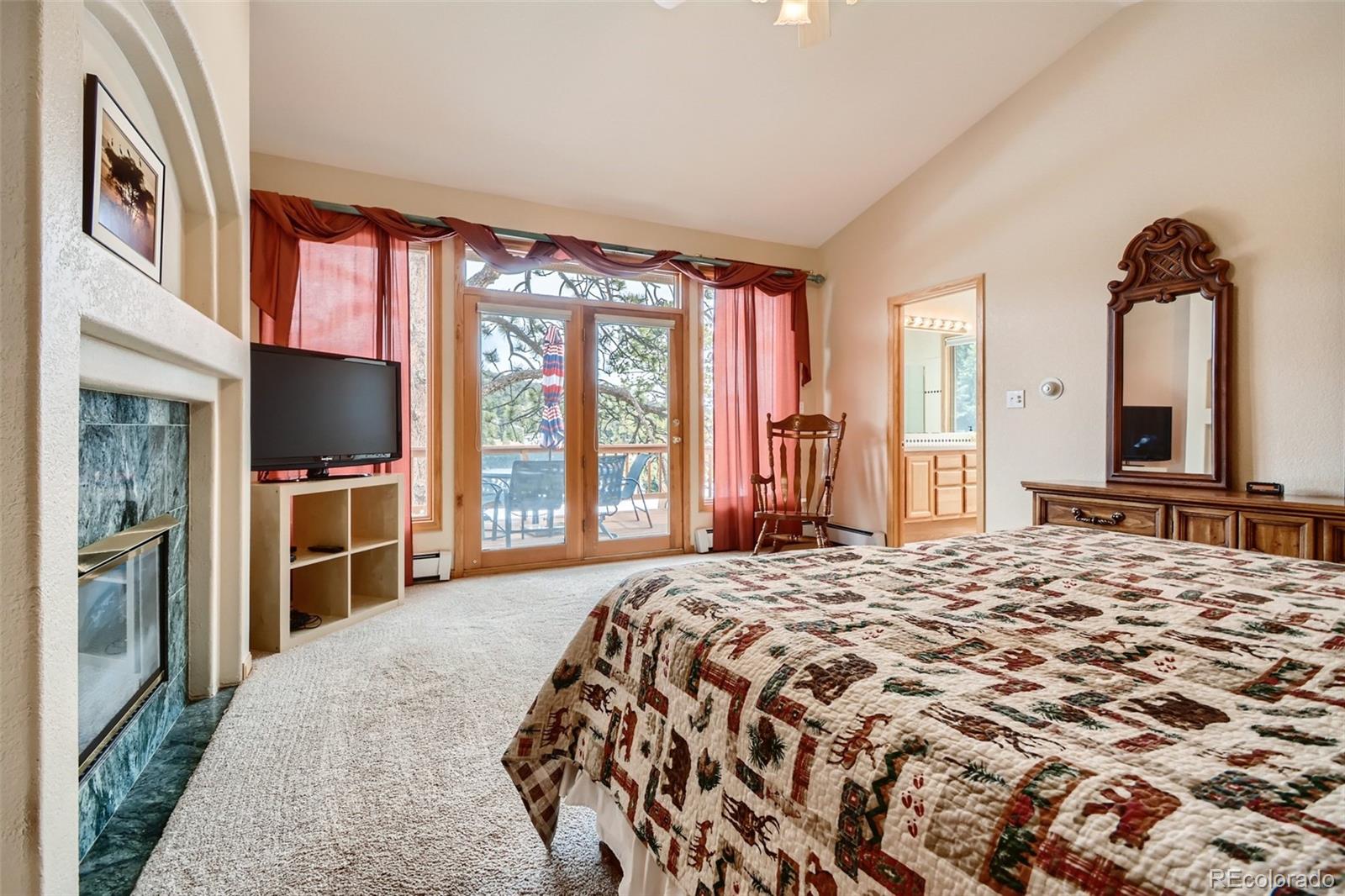 1634 Muirfield Lane Evergreen, CO 80439 - Photo 15 of 40 a bedroom with a large bed and a flat tv screen on dresser