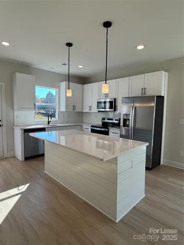 a large kitchen with stainless steel appliances kitchen island granite countertop a refrigerator a oven a sink and a wooden floors