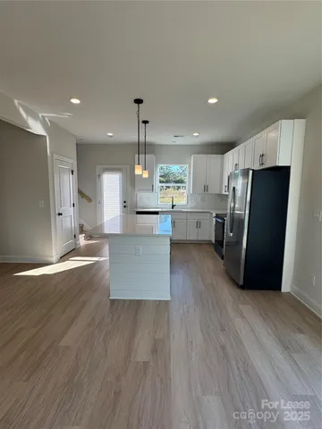 a large kitchen with stainless steel appliances a large counter top and wooden floors