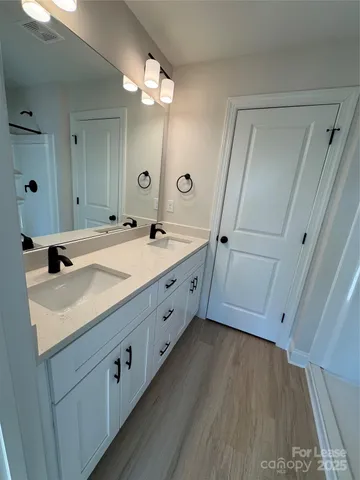 a spacious bathroom with a double vanity sink and mirror with shower