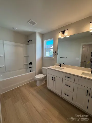 a spacious bathroom with double sink a large mirror and a bathtub