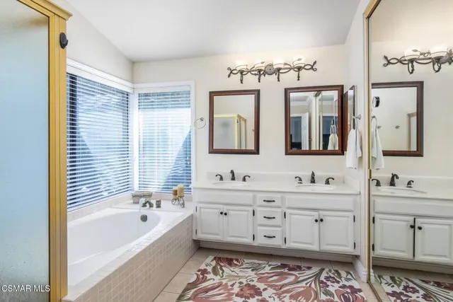 a bathroom with a double vanity sink mirror and bathtub