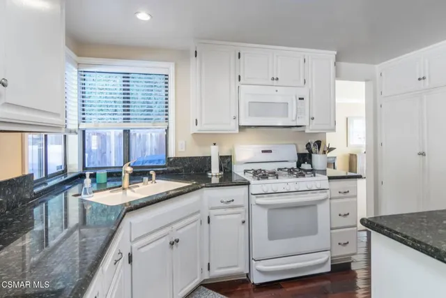 a kitchen with granite countertop white cabinets and white appliances