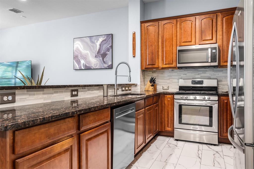 5019 Morris Avenue, Unit 22 Addison, TX 75001 - Photo 9 of 31 a kitchen with granite countertop stainless steel appliances a stove sink and microwave