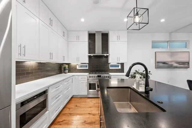 a kitchen with stainless steel appliances granite countertop a sink a stove and cabinets