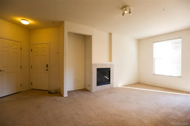 an empty room with windows and fireplace