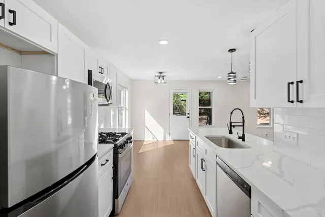 a kitchen with stainless steel appliances a sink stove and refrigerator