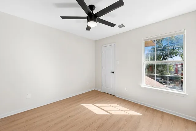 a view of empty room with wooden floor and fan
